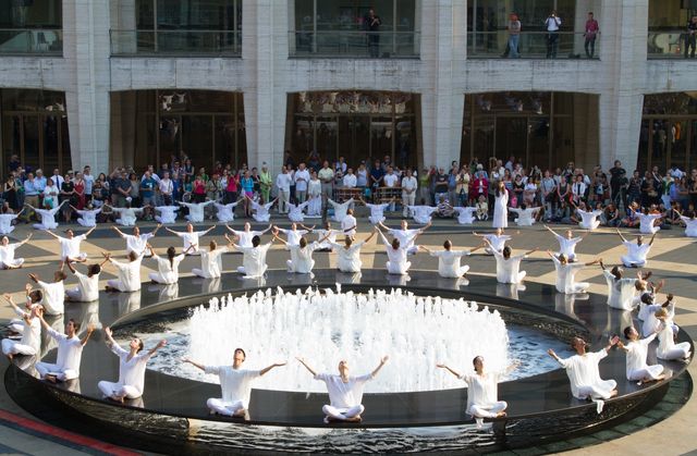 Dancers dressed in white surrounding a fountain